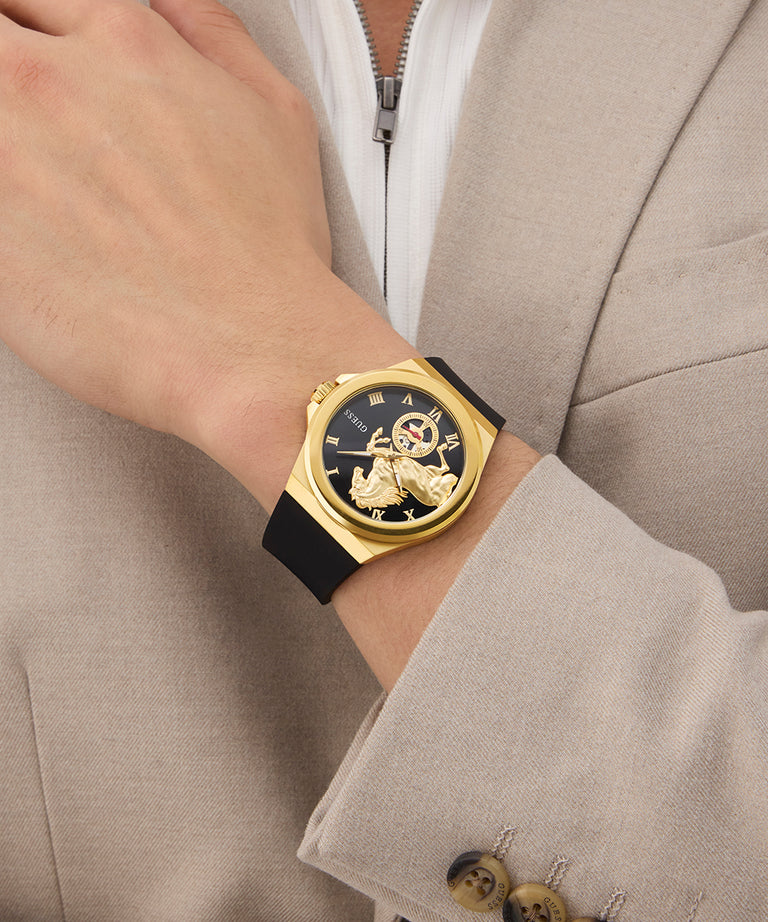 Gold GUESS Mens Limited Edition Lunar New Year Black Gold Tone Analog Watch with black strap on a wrist, wearing a beige suit jacket.