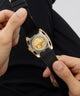GUESS Mens Black Gold Tone Automatic Watch caseback held by a person against a dark background