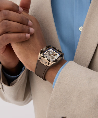 Close-up of a person wearing a luxurious watch with a detailed face and brown leather strap.