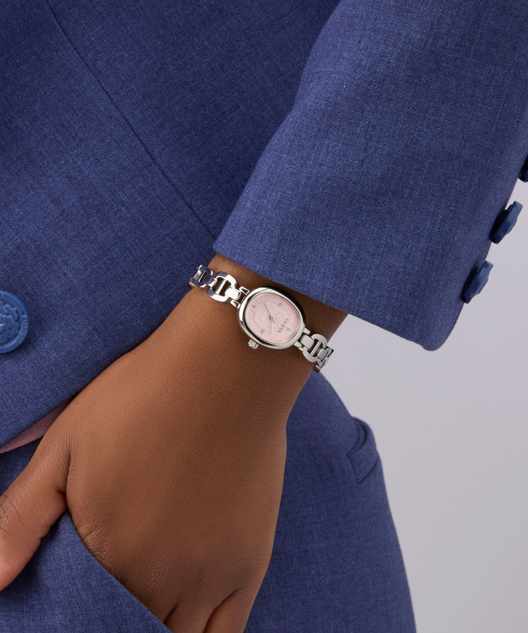 Person wearing a silver watch on a blue suit with a gray background