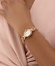 GUESS Ladies Rose Gold Tone Analog Watch on a wrist with a soft pink background