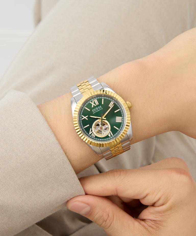 GUESS Mens 2-Tone Automatic Watch with green face on a wrist against a neutral background