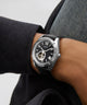 GUESS Mens Black Silver Tone Automatic Watch on a person's wrist with a blurred background