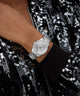 Silver GUESS Ladies Silver Tone Analog Watch on a wrist with a black sequin outfit