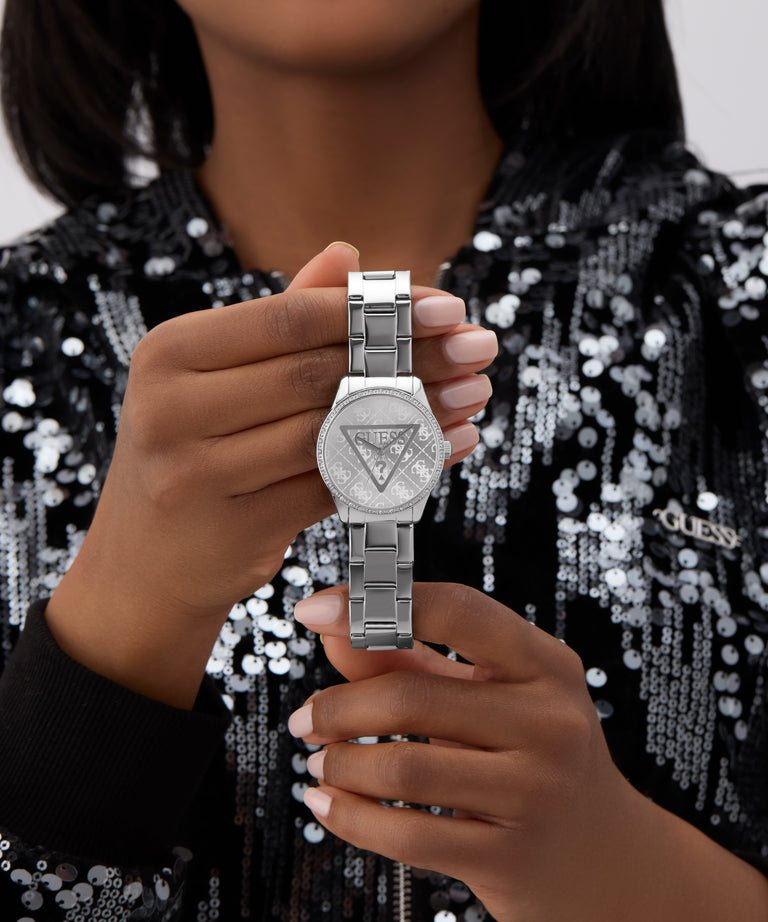 Person holding a silver GUESS Ladies Silver Tone Analog Watch with a triangle design, wearing a black sequin top.