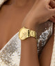 Gold watch on a wrist with a sequined garment in the background GUESS Ladies Gold Tone Analog Watch