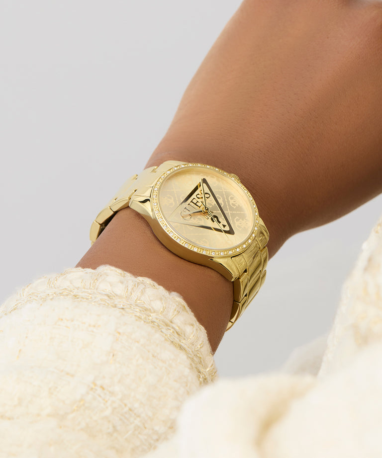 GUESS Ladies Gold Tone Analog Watch on a wrist with a blurred background