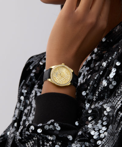 Gold GUESS Ladies Black Gold Tone Analog Watch on a wrist with a black sequin garment