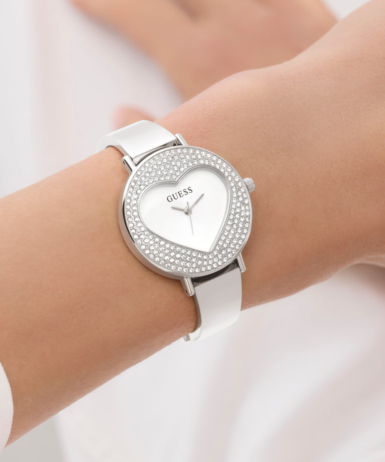 Silver Guess watch with heart-shaped face on a wrist against a light background