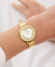 GUESS Ladies Gold Tone Analog Watch with heart-shaped face on a wrist against a white background