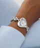 Silver heart-shaped GUESS Ladies Valerie Silver Tone Analog Watch on a wrist with a light blue sweater