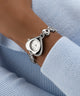 GUESS Ladies Valerie Silver Tone Analog Watch on a wrist with a light blue sweater