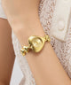 GUESS Ladies Valerie Gold Tone Analog Watch on a person's wrist with a white lace garment in the background