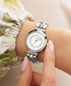 Silver Guess watch on a wrist with a blurred background
