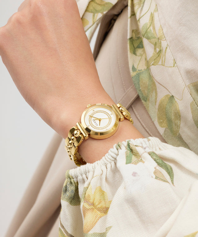Gold GUESS Ladies Gold Tone Analog Watch on a wrist with a floral-patterned garment