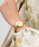 Gold GUESS Ladies Gold Tone Analog Watch on a wrist with a floral-patterned garment