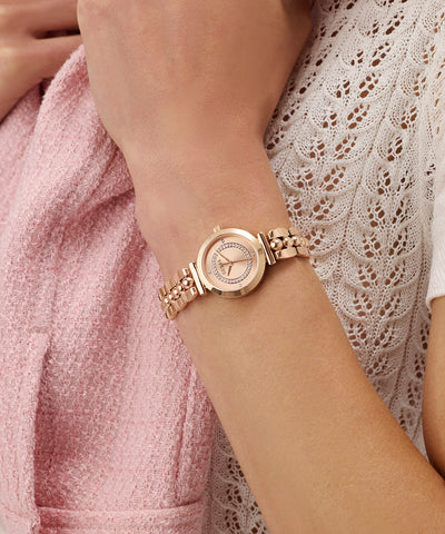 GUESS Ladies Rose Gold Tone Analog Watch on a wrist with a soft focus background