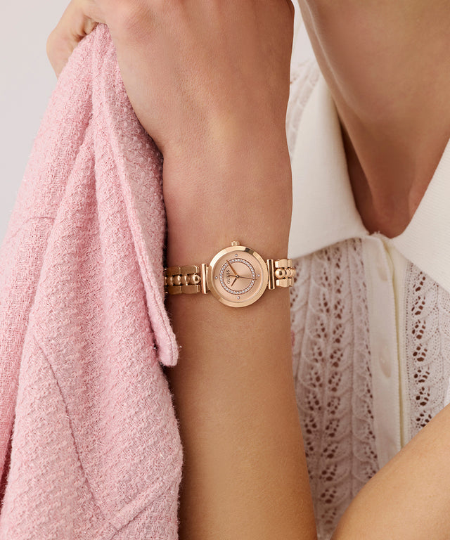 GUESS Ladies Rose Gold Tone Analog Watch on a wrist with a pink towel and white lace garment in the background