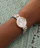 Rose gold and silver watch on a wrist with a lace background