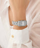 Silver GUESS Ladies Silver Tone Analog Watch on a wrist with a white shirt background
