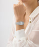 GUESS Ladies Silver Tone Analog Watch on a wrist with a white shirt against a light background