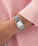 Silver GUESS Ladies Silver Tone Analog Watch on a wrist with a pink textured background