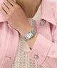 Silver GUESS Ladies Silver Tone Analog Watch on a wrist with a pink coat