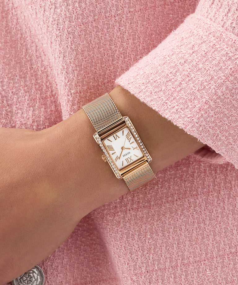 GUESS Ladies Rose Gold Tone Analog Watch on a wrist with a pink textured background