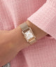 GUESS Ladies Rose Gold Tone Analog Watch on a wrist with a pink textured background