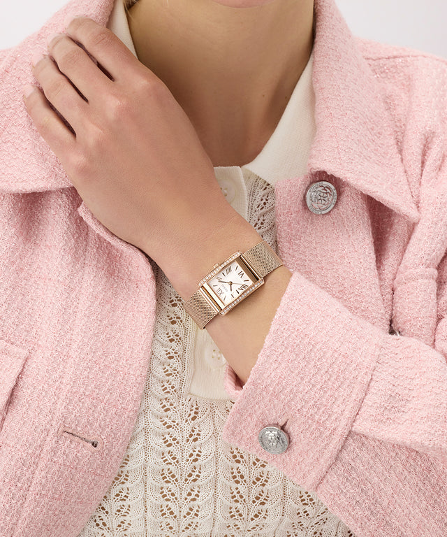 Person wearing a GUESS Ladies Rose Gold Tone Analog Watch on a pink coat with a white lace garment underneath.