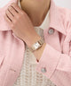 Person wearing a GUESS Ladies Rose Gold Tone Analog Watch on a pink coat with a white lace garment underneath.
