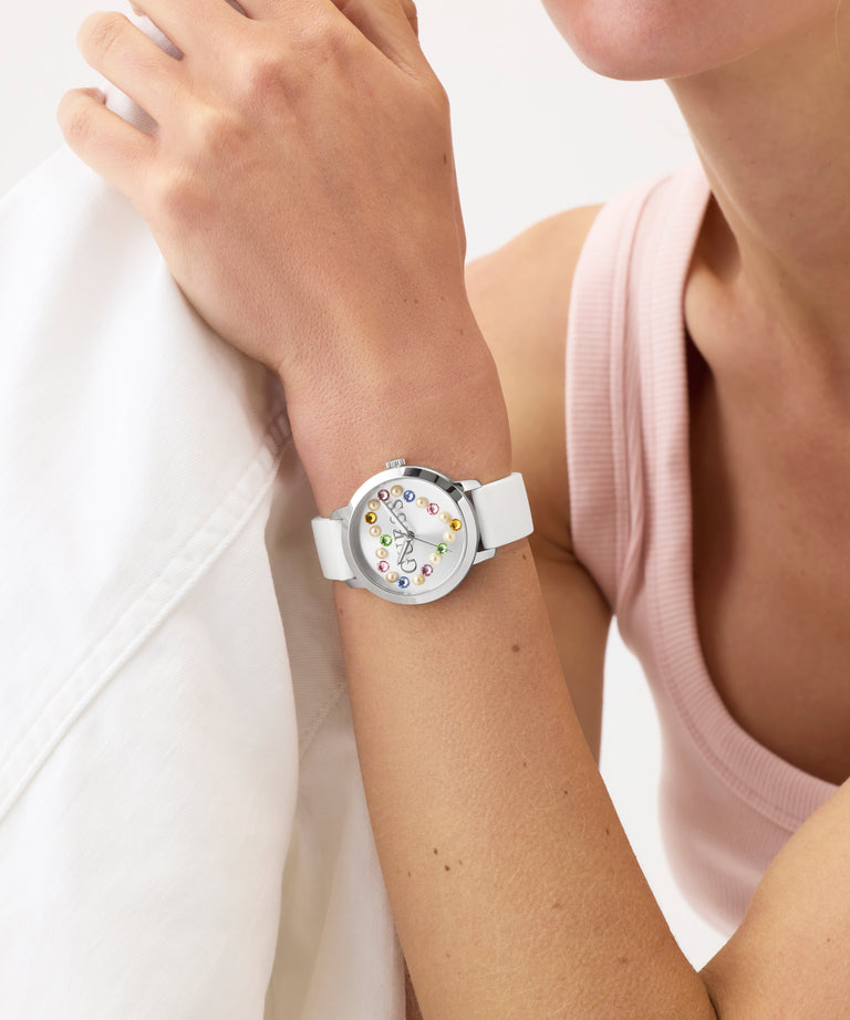 Person wearing a GUESS Ladies White Silver Tone Analog Watch GUESS Ladies White Silver Tone Analog Watch with a colorful face on a light background