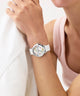Person wearing a GUESS Ladies White Silver Tone Analog Watch GUESS Ladies White Silver Tone Analog Watch with a colorful face on a light background