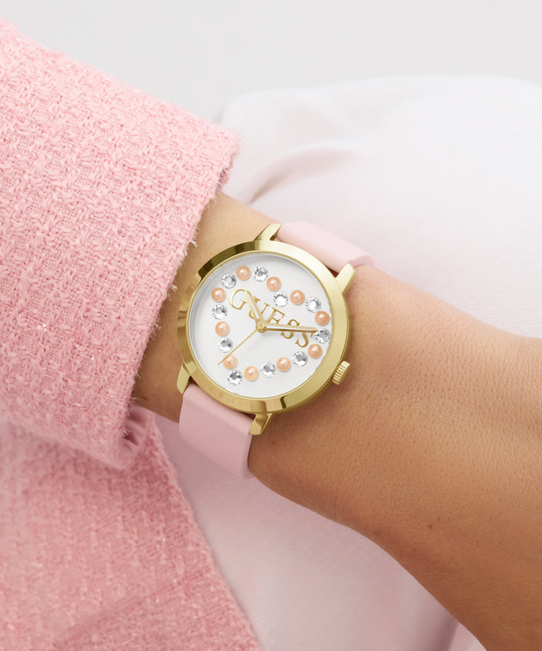 GUESS Ladies Pink Gold Tone Analog Watch with pink strap on a wrist against a light background