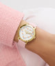 GUESS Ladies Pink Gold Tone Analog Watch with pink strap on a wrist against a light background