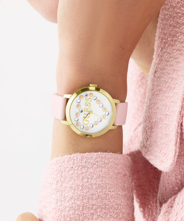 GUESS Ladies Pink Gold Tone Analog Watch with pink strap worn on a wrist, against a light background