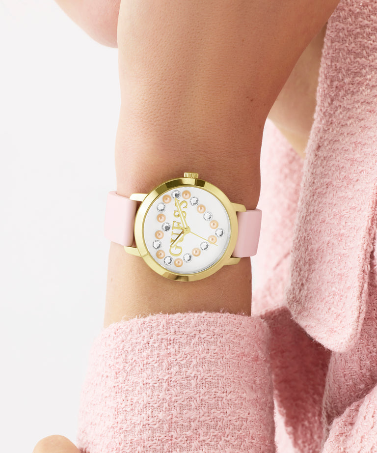 GUESS Ladies Pink Gold Tone Analog Watch with pink strap worn on a wrist, against a light background