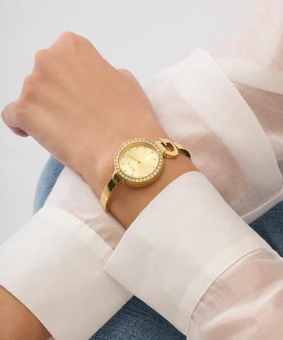 GUESS Ladies GOLD TONE Analog Watch on a wrist with a light background