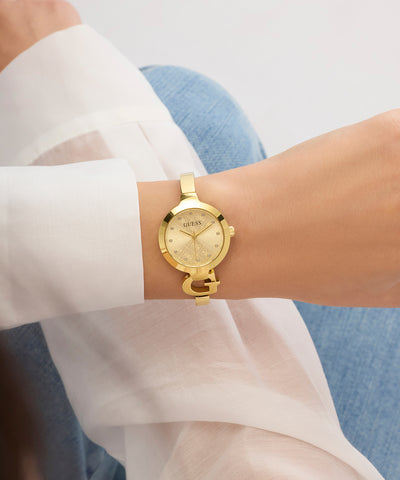 GUESS Ladies GOLD TONE Analog Watch on a wrist with a white shirt and blue jeans