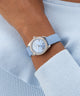 Wrist wearing a light blue GUESS Ladies Mini Luna Blue Silver Tone Analog Watch with a matching light blue sweater