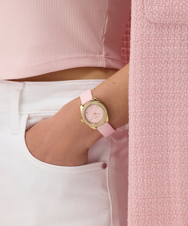 GUESS Ladies Mini Luna Pink Gold Tone Analog Watch on a wrist with a pink background