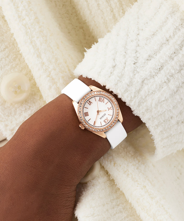 Rose gold watch with white strap on a wrist against a soft, light background