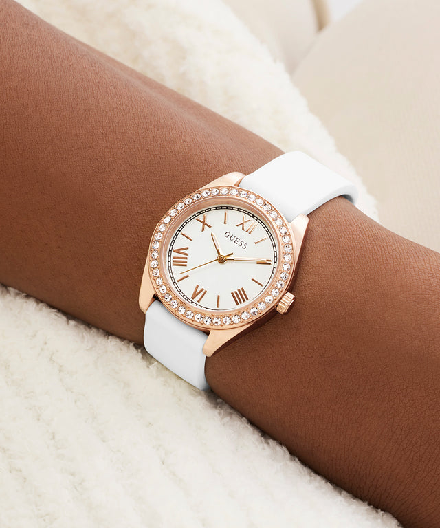 Rose gold watch with white strap on wrist against a neutral background