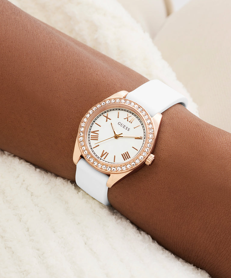 Rose gold watch with white strap on wrist against a neutral background