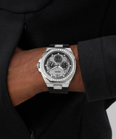 GUESS Mens Black Silver Tone Analog Watch with diamond accents on a wrist, wearing a black suit.