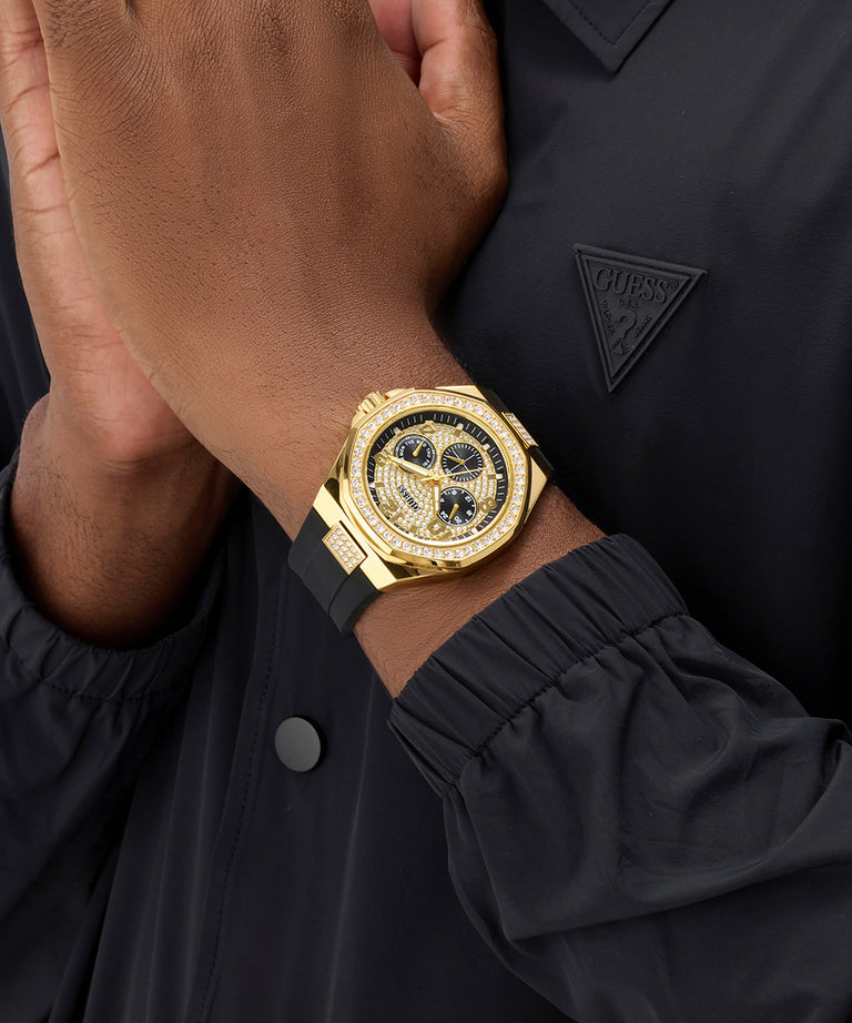 GUESS Mens BLACK GOLD TONE Analog Watch on a wrist with a black coat and Guess logo