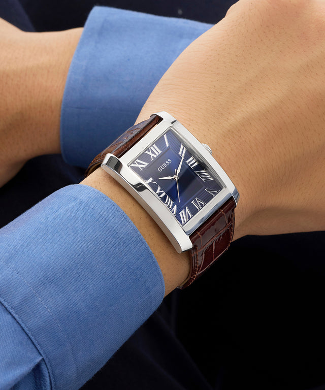 GUESS Mens BROWN SILVER TONE Analog Watch on a wrist with a blue shirt sleeve