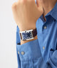 Person wearing a GUESS Mens BROWN SILVER TONE Analog Watch with a blue shirt on a light gray background
