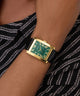 GUESS Mens BLACK GOLD TONE Analog Watch on a wrist with a black and white patterned fabric background
