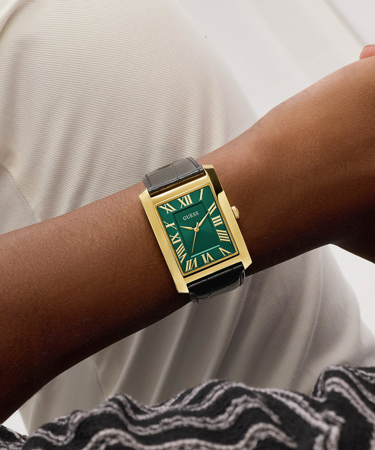 GUESS Mens BLACK GOLD TONE Analog Watch with green face on a wrist against a white background